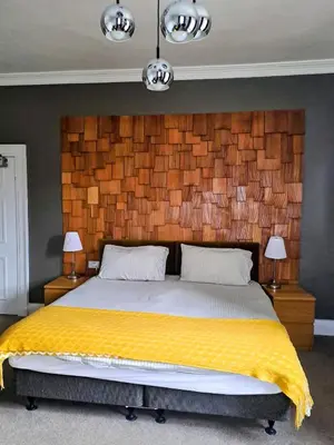 a bedroom with a large bed with a wooden headboard at Brewery house in Newton Stewart