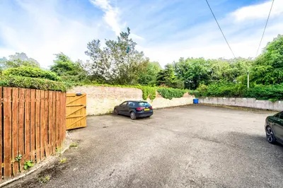 a car parked in a parking lot next to a fence at Snug 1 Bed Apartment in Edinburgh's Juniper Green in Edinburgh