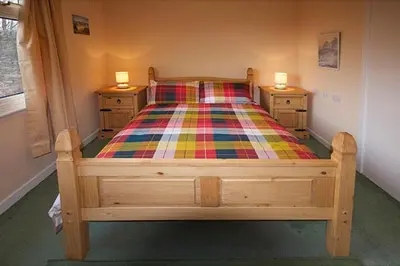 a bedroom with a wooden bed with two night stands at Correay Cottage in Salen