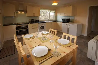 a kitchen with a wooden table with plates and wine glasses at Correay Cottage in Salen