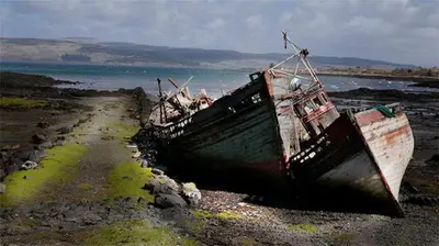 two boats sitting on the shore of a beach at Correay Cottage in Salen