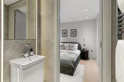 a bedroom with a bed and a sink and a mirror at Stylish 2-Bedroom Flat On Seven Sisters Rd in Moffat