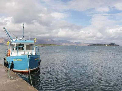 a blue boat tied to a dock in the water at Lurach House in Appin