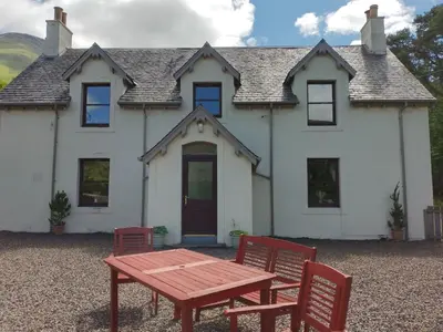 a table and chairs in front of a house at Holiday Home Benmore Farm House in Stirling mit Bergblick by Interhome in Crianlarich