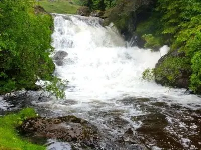 a river with white water rushing down a hill at Holiday Home Benmore Farm House in Stirling mit Bergblick by Interhome in Crianlarich