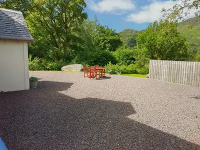 a patio with two red chairs and a fence at Holiday Home Benmore Farm House in Stirling mit Bergblick by Interhome in Crianlarich