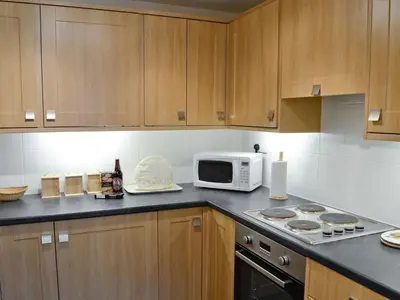 a kitchen with wooden cabinets and a microwave at Holiday Home Gehöft 2 by Interhome in Tweedsmuir