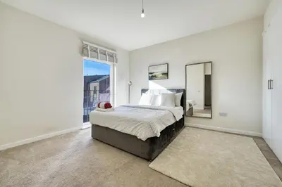 a white bedroom with a bed and a large window at Stylish and Morden 3Bed House Glasgow City Centre in Glasgow