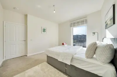 a white bedroom with a large bed and a window at Stylish and Morden 3Bed House Glasgow City Centre in Glasgow
