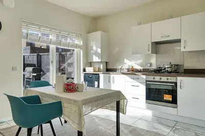 a kitchen with a table and two chairs and a kitchen with white cabinets at Stylish and Morden 3Bed House Glasgow City Centre in Glasgow