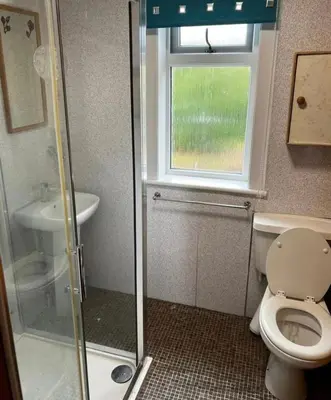 a bathroom with a toilet and a sink and a window at Lynndale in Carradale