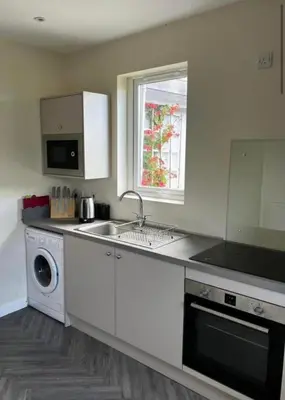 a white kitchen with a sink and a dishwasher at Lynndale in Carradale