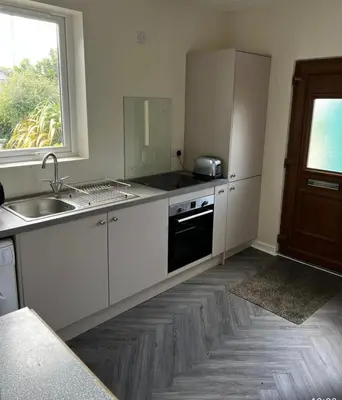 a kitchen with white cabinets and a sink and a window at Lynndale in Carradale