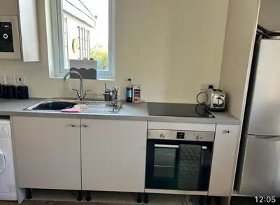a kitchen with white cabinets and a sink and a window at Lynndale in Carradale