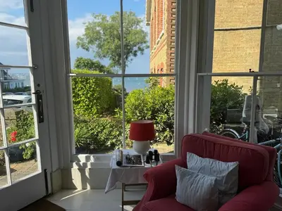 a living room with a red chair and a window at Regents House, ground floor apartment with sea views in Moffat