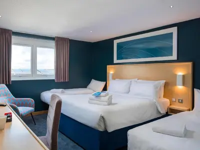 a hotel room with two beds and a desk at Travelodge Edinburgh Dreghorn in Edinburgh