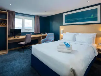 a hotel room with a large bed and a desk at Travelodge Edinburgh Dreghorn in Edinburgh