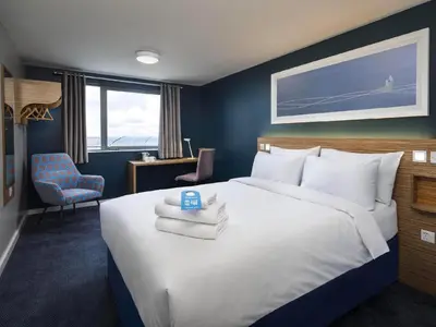 a bedroom with a large bed with towels on it at Travelodge Falkirk in Polmont