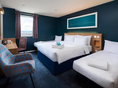 a hotel room with two beds and a chair at Travelodge Falkirk in Polmont