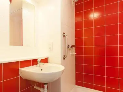 a bathroom with a sink and red tiles at Travelodge Falkirk in Polmont
