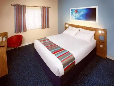 a hotel room with a bed and a red chair at Travelodge Kinross M90 in Kinross