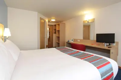 a hotel room with a large white bed and a desk at Travelodge Kinross M90 in Kinross