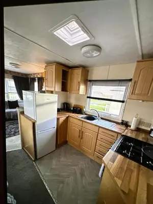 a kitchen with wooden cabinets and a white refrigerator at Sandylands caravan park in Stevenston