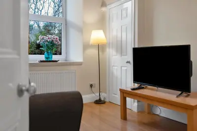 a living room with a flat screen tv on a table at Charming City View Apartment with Modern Comforts in Edinburgh
