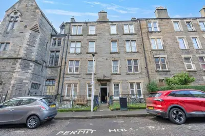 two cars parked in front of an old building at Charming City View Apartment with Modern Comforts in Edinburgh