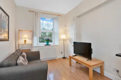 a living room with a couch and a flat screen tv at Charming City View Apartment with Modern Comforts in Edinburgh