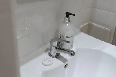 a bottle of detergent sitting on a bathroom sink at Charming City View Apartment with Modern Comforts in Edinburgh