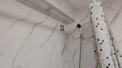 a shower in a bathroom with white marble walls at Cosy Retreat - Suite 5 in Hamilton