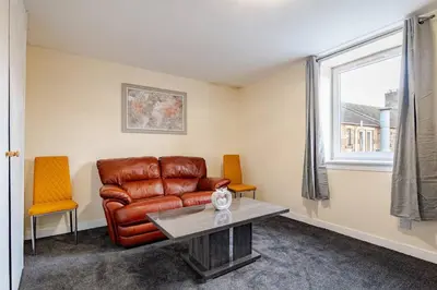 a living room with a leather couch and two chairs at Cosy Retreat - Suite 5 in Hamilton