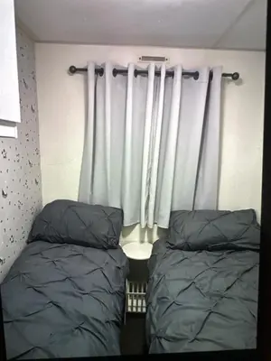 a bedroom with two beds and a window with curtains at Sandylands caravan park in Stevenston