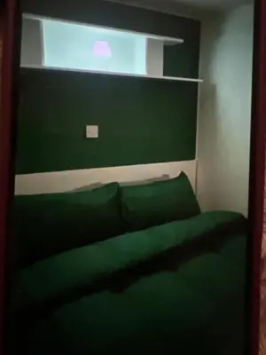 a bedroom with a green bed with a window at Sandylands caravan park in Stevenston