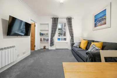 a living room with a couch and a flat screen tv at Stylish 1BR Central Oban Retreat in Oban