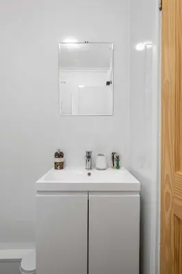 a white bathroom with a sink and a mirror at Stylish 1BR Central Oban Retreat in Oban