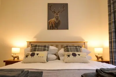 a bedroom with a bed with pillows with a deer on it at Stylish 1BR Central Oban Retreat in Oban