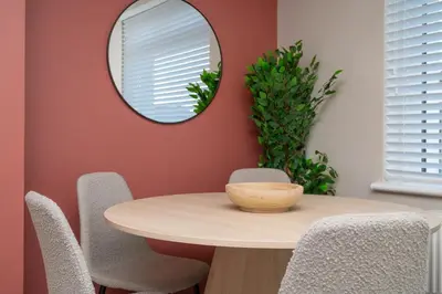 a dining room with a table and a mirror at Vacant Nests Unique 4BR home The Muirhouse in Motherwell