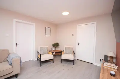 a living room with two chairs and a table at Vacant Nests Unique 4BR home The Muirhouse in Motherwell