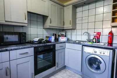a kitchen with white cabinets and a washer and a dishwasher at Burnvale Apartment in Livingston