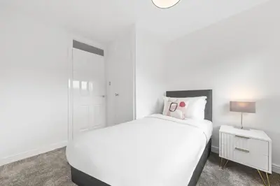 a white bedroom with a white bed and a nightstand at The Brora in High Blantyre