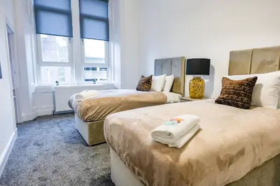 two beds in a room with two windows and a room with two beds at Cambridge Apartment in Glasgow