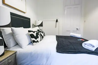 a white bed with white pillows and a black blanket at Cambridge Apartment in Glasgow