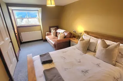 a bedroom with a large bed and a couch at 3 Bed House - Mountain Views Bbq Firepit in Dunoon