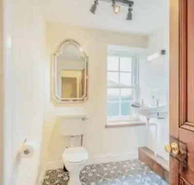 a bathroom with a toilet and a sink and a mirror at 3 Bed House - Mountain Views Bbq Firepit in Dunoon