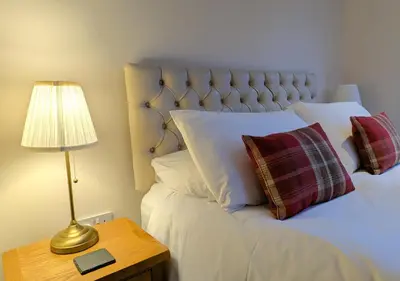 a bedroom with a bed with a lamp on a table at Balmore - 3 Bedroom Townhouse, heart of Killin in Killin