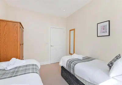 two beds in a room with white walls at Balmore - 3 Bedroom Townhouse, heart of Killin in Killin