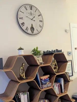 a clock hanging on a wall above a book shelf at Balmore - 3 Bedroom Townhouse, heart of Killin in Killin