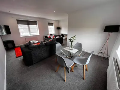 a living room with a glass table and chairs at 2 Bed Apartment Sleeps 4 -Near Airport -WiFi & Tv in Renfrew